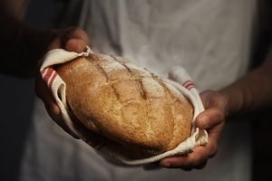 Man Holding Loaf of Bread